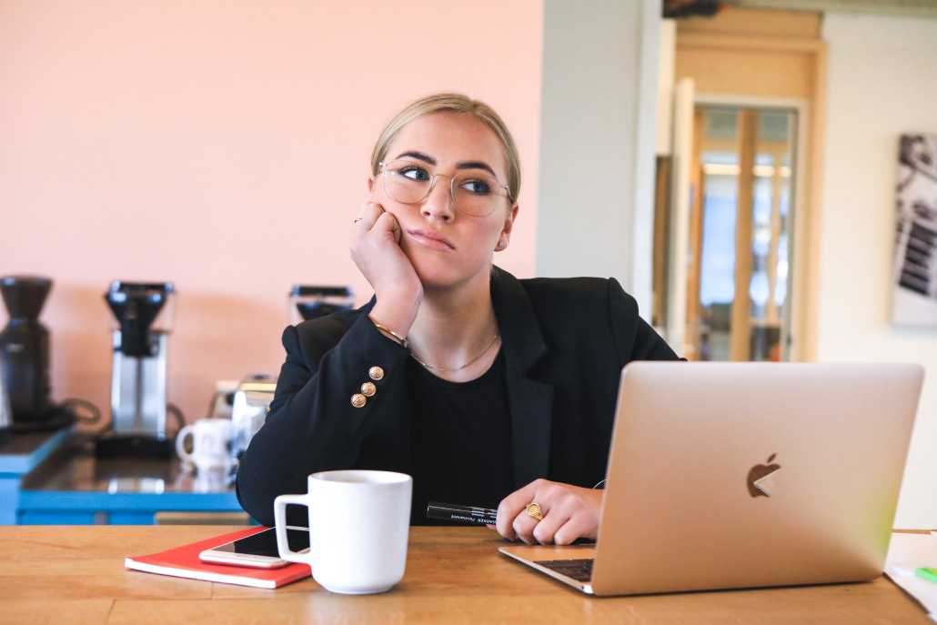 Woman daydreaming at her workplace, showing a visible lack of interest and engagement with her work.